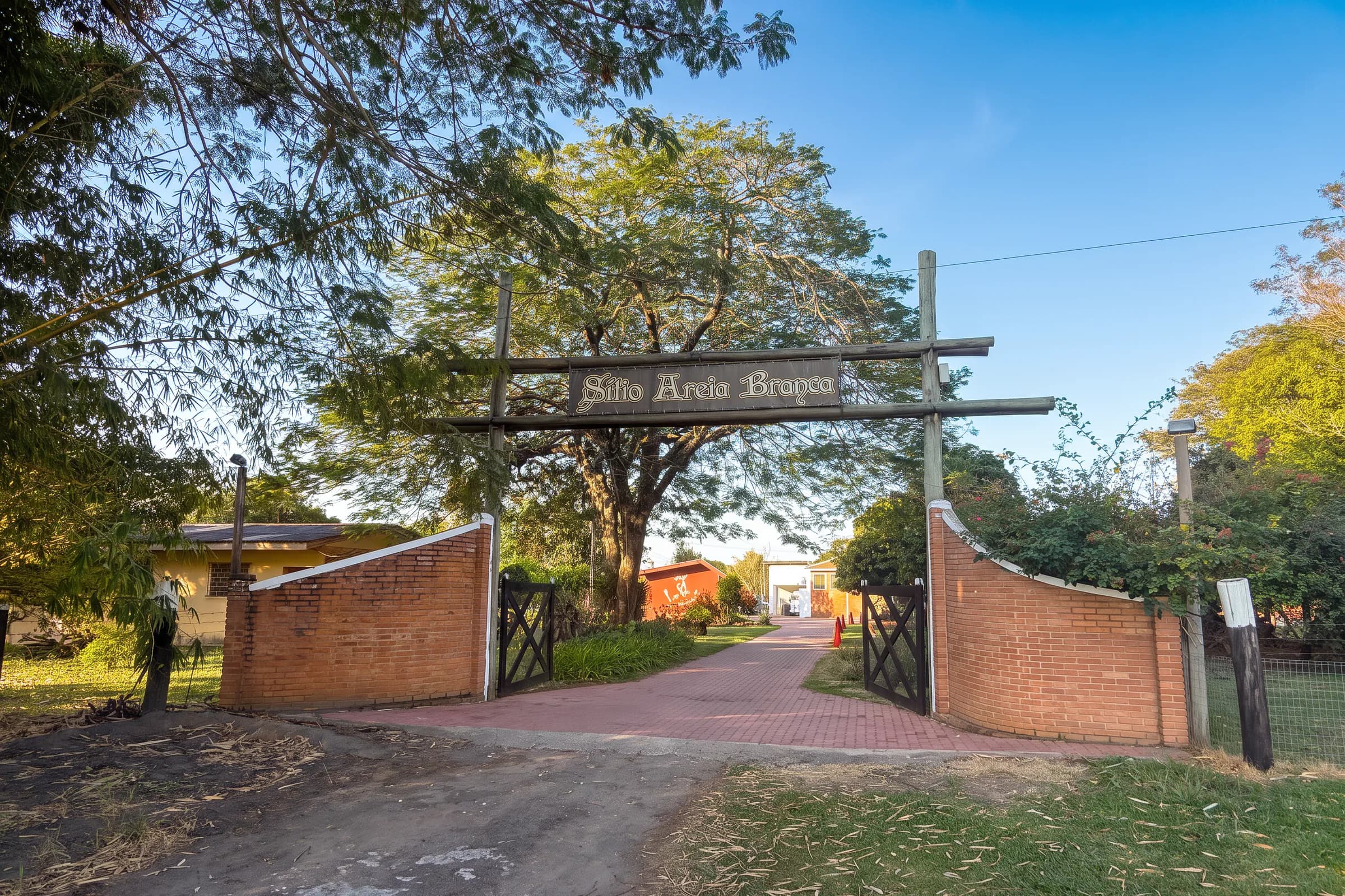 Entrada do Sítio Areia Branca, em Tietê (SP), com a placa de madeira sobre o portão de tijolos
