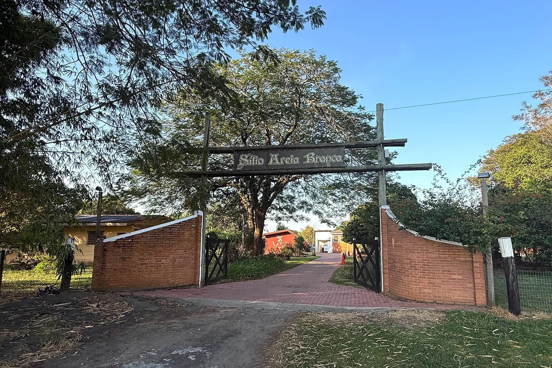 Entrada do Sítio Areia Branca, em Tietê (SP), com a placa de madeira sobre o portão de tijolos